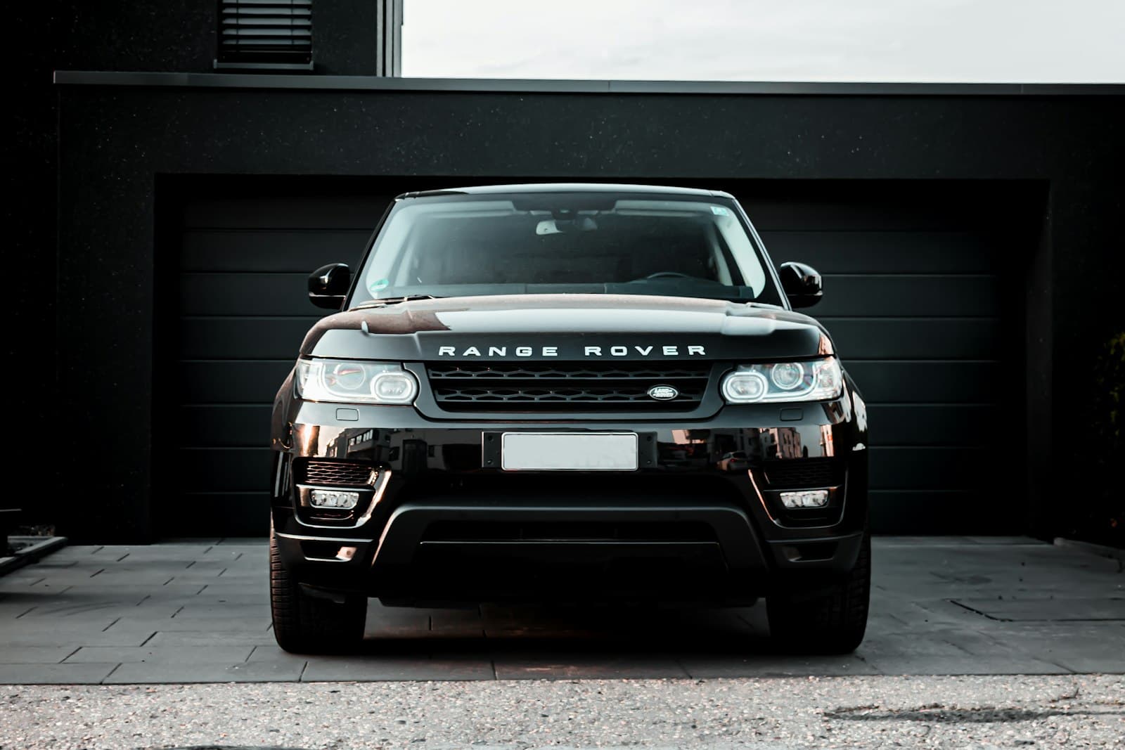 Black Range Rover Sport parked in front of a dark garage